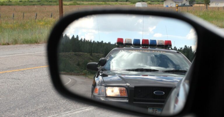 image of car's side mirror with police car in reflection